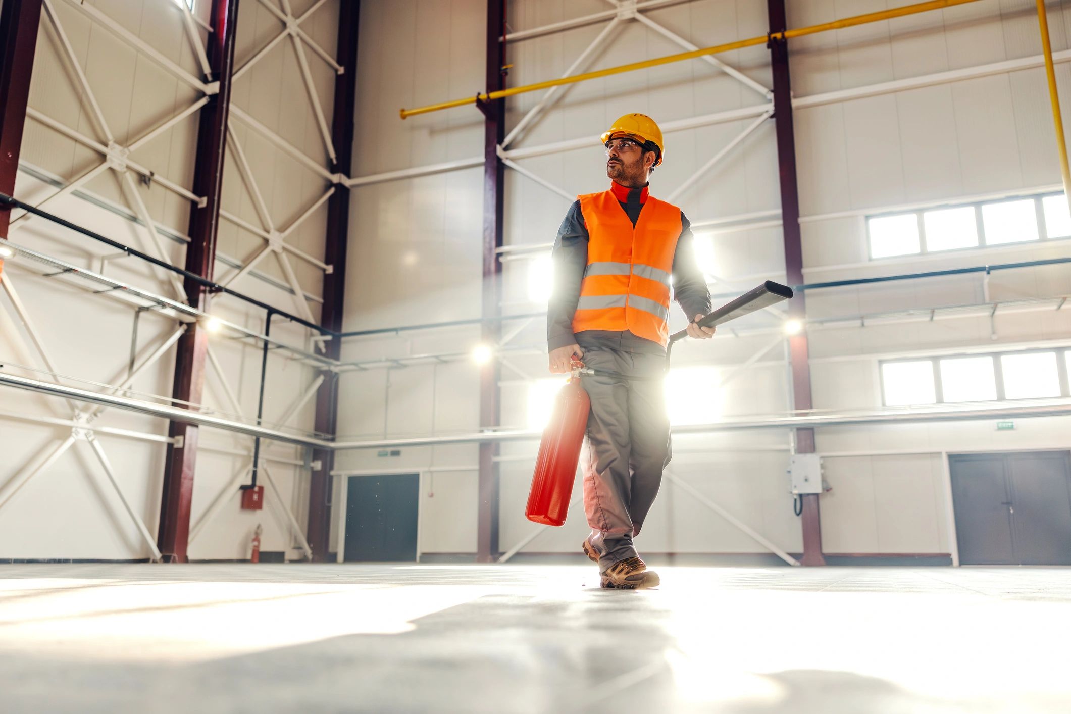 Engineer carrying a fire extinguisher through a commercial facility